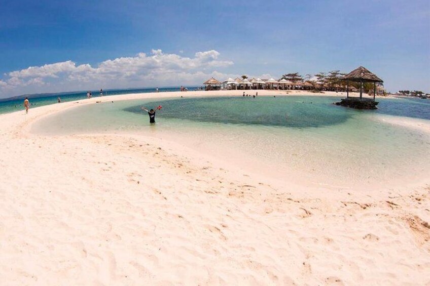 Une plage à l’eau turquoise et limpide, un rivage sablonneux, et quelques personnes qui se promènent. 2