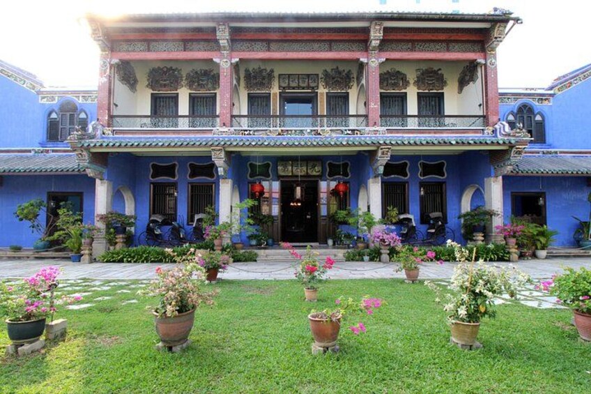 A traditional building with a blue facade, a balcony, and potted plants in the foreground. 3