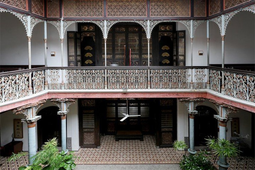 A courtyard with a balcony, patterned floor, and potted plants. 5