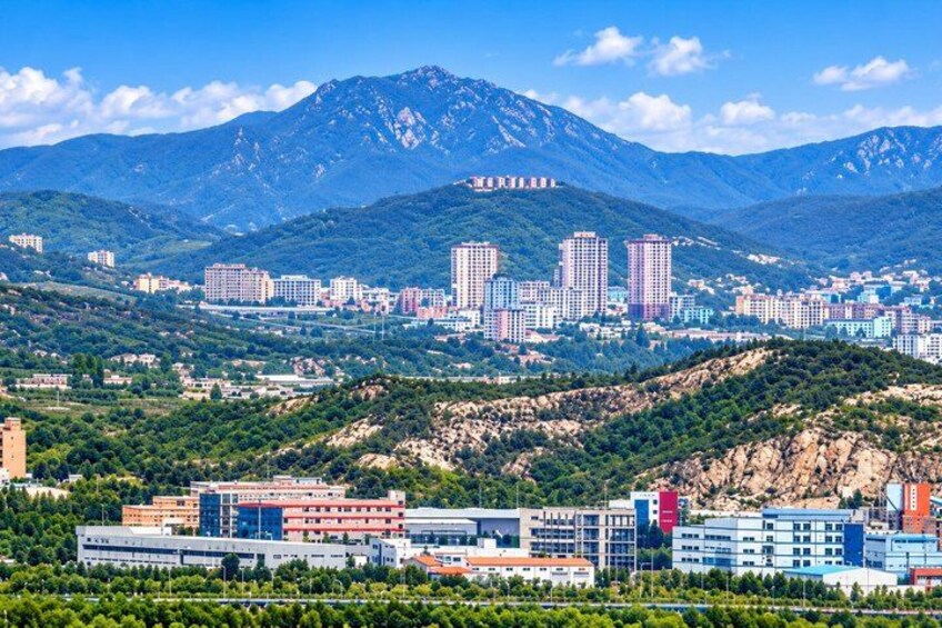 A cityscape with a mountain in the background, modern buildings, and a clear sky. 3