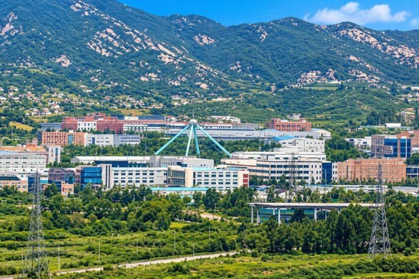 A cityscape with modern buildings, a prominent bridge, and mountains in the background. 5
