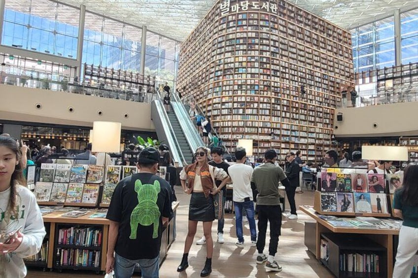Ein Bibliotheksinneres mit Bücherregalen, einer Treppe und Personen, die stöbern. 5