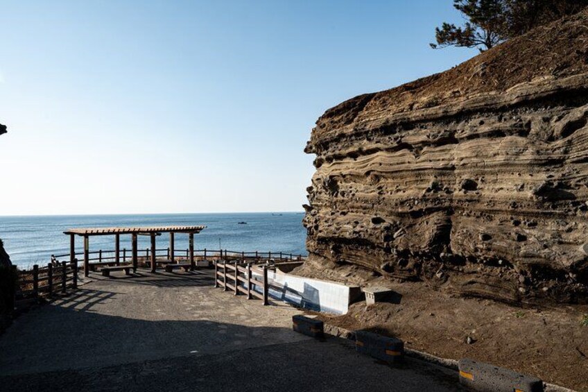 A coastal area with a wooden pier, a rocky cliff, and the sea. 4