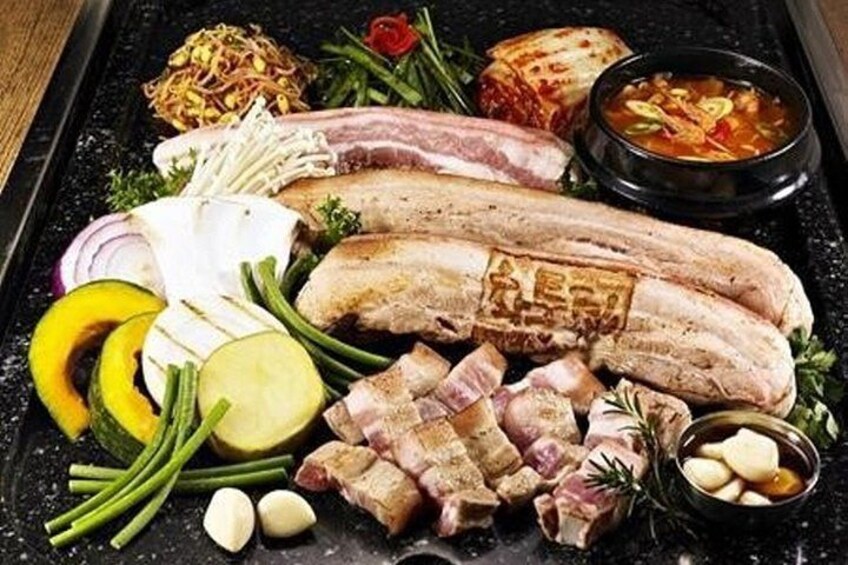 A variety of meats, vegetables, and a bowl of soup on a black tray. 5