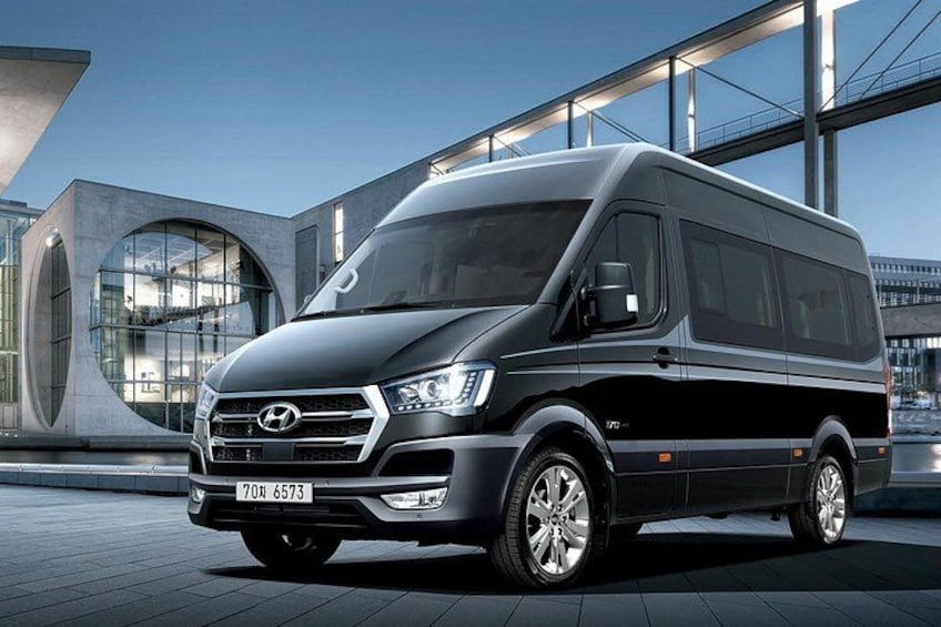 A black Hyundai van parked in front of a modern building with large windows and a curved architectural feature. 5