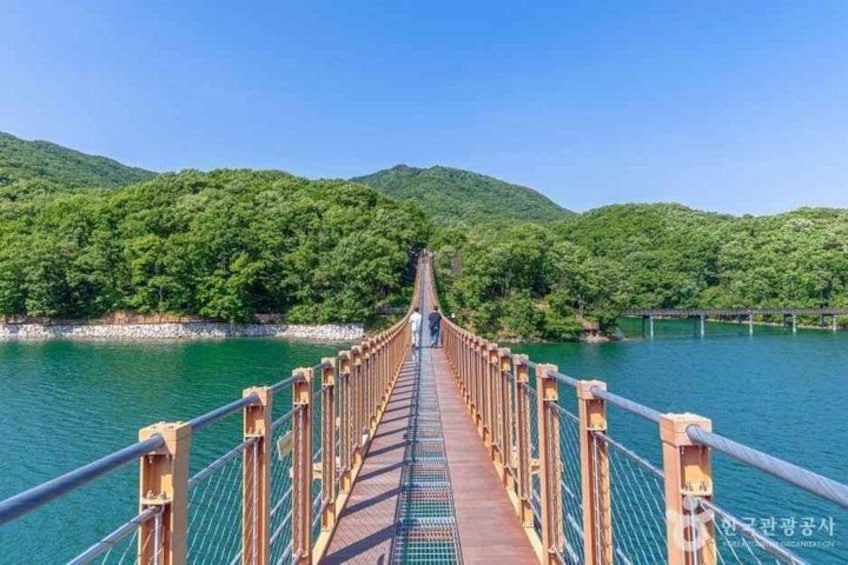 A suspension bridge over a body of water with green hills in the background. 2