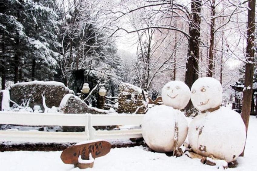 Zwei Schneemänner mit Gesichtern, eine verschneite Bank und ein verschneiter Wagen in einer verschneiten Winterlandschaft. 5