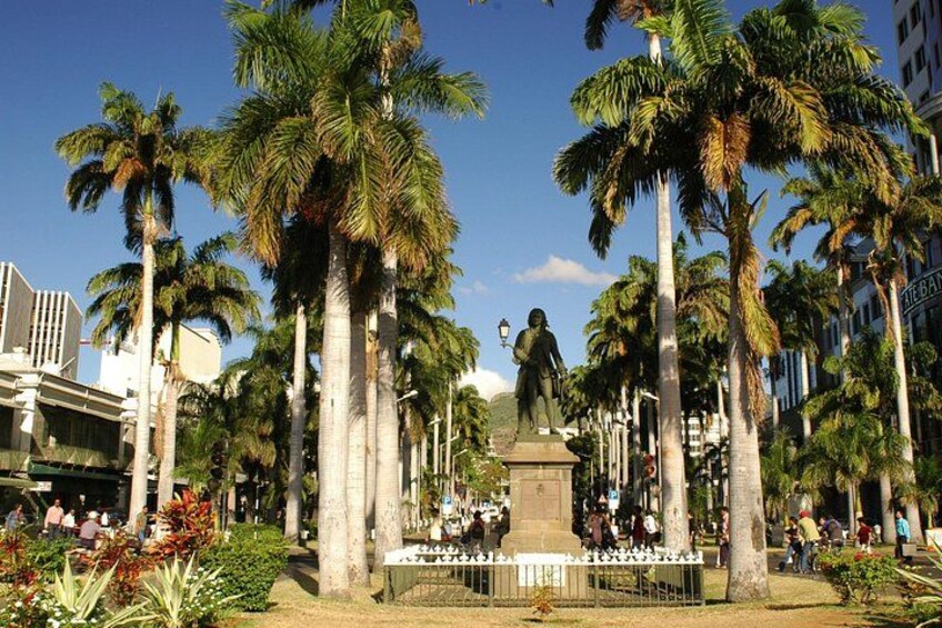 A statue surrounded by palm trees and buildings. 5