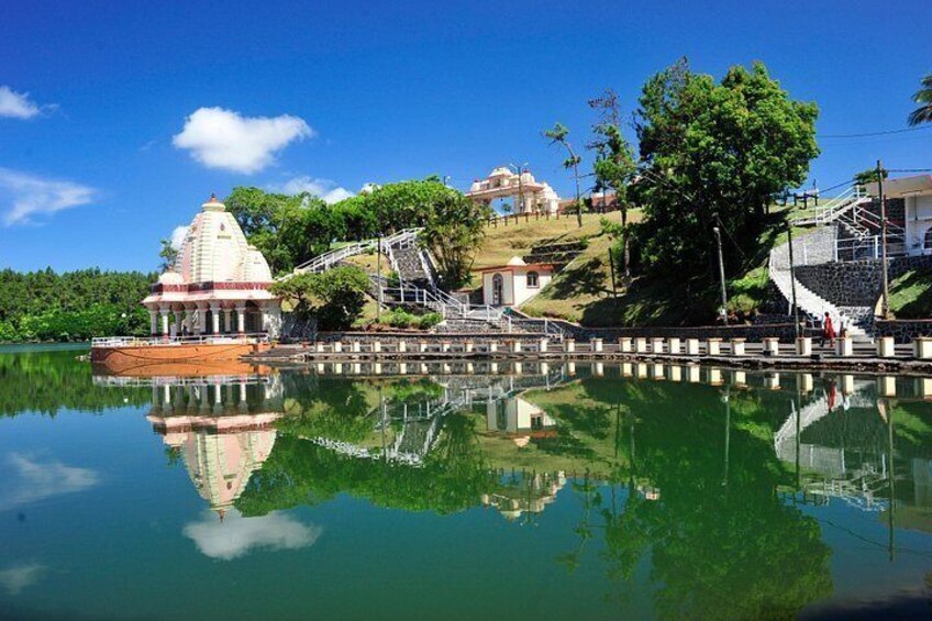 A temple with a reflection in the water, surrounded by greenery and a clear sky. 2