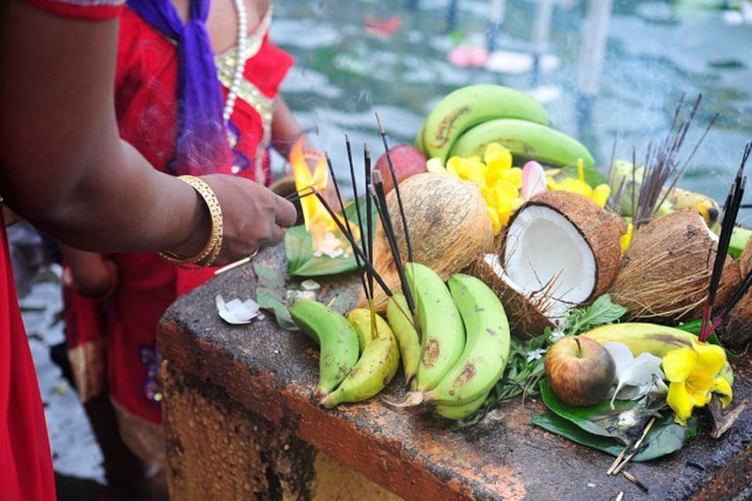 Una persona realizando un ritual con plátanos, cocos y palitos de incienso. 2