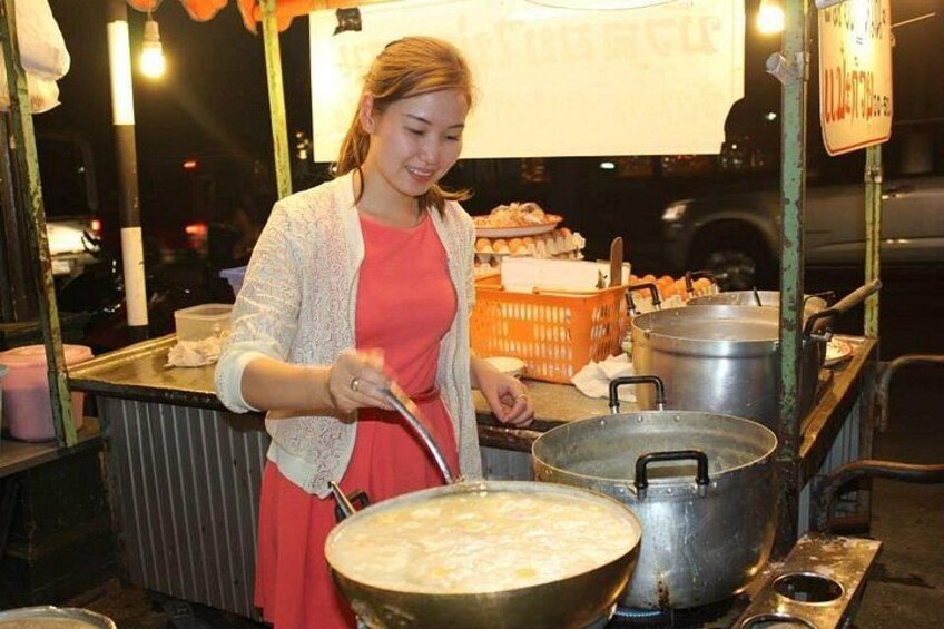 A person cooking in a large pot at a street food stall. 3