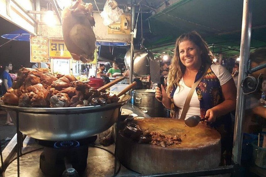 A street food vendor cooking outdoors with a large pot and a deep fryer. 1