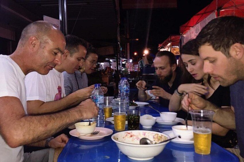 A group of people dining at a table with bowls, cups, and bottles. 2