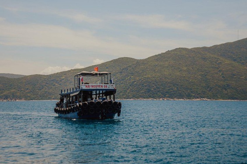 A boat named Hai Nguyen 08 on a body of water with a mountainous landscape in the background. 3