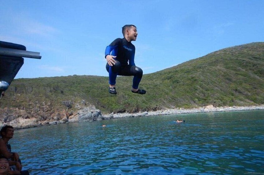 Una persona saltando desde un bote hacia el agua, con un paisaje montañoso al fondo. 4