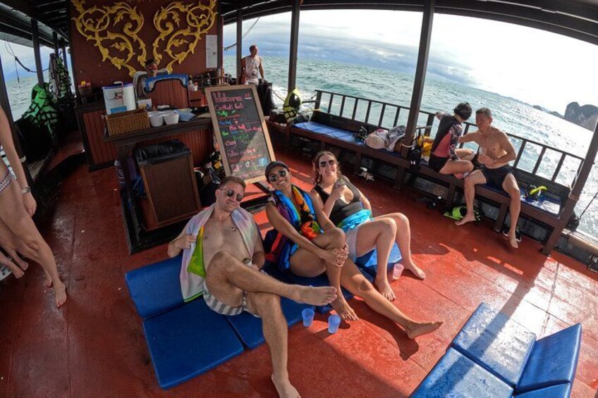 A boat deck with people relaxing, a bar area, and a view of the ocean. 2