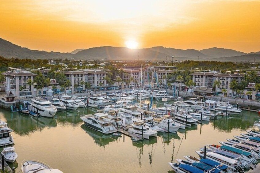A marina with boats docked, buildings, and a sunset in the background. 5
