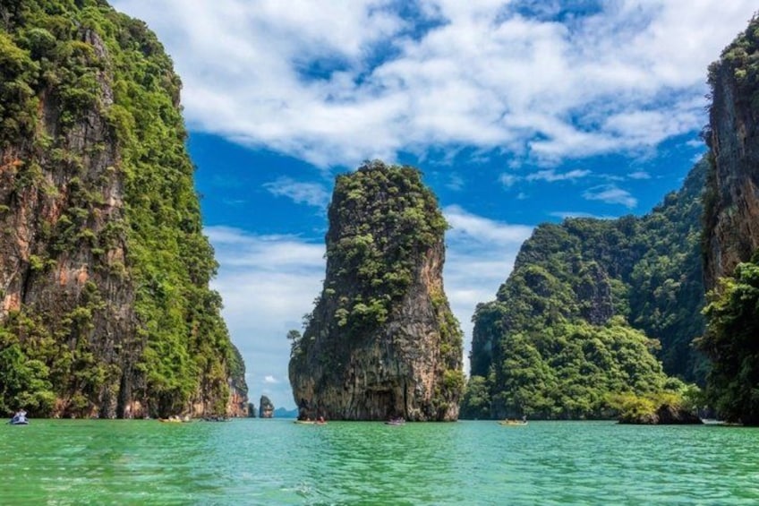 A clear waterway flanked by tall, green rock formations under a blue sky. 4