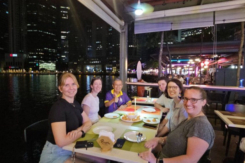 Un gruppo di persone che cena in un ristorante all'aperto, con una vista sulla città sullo sfondo. 3