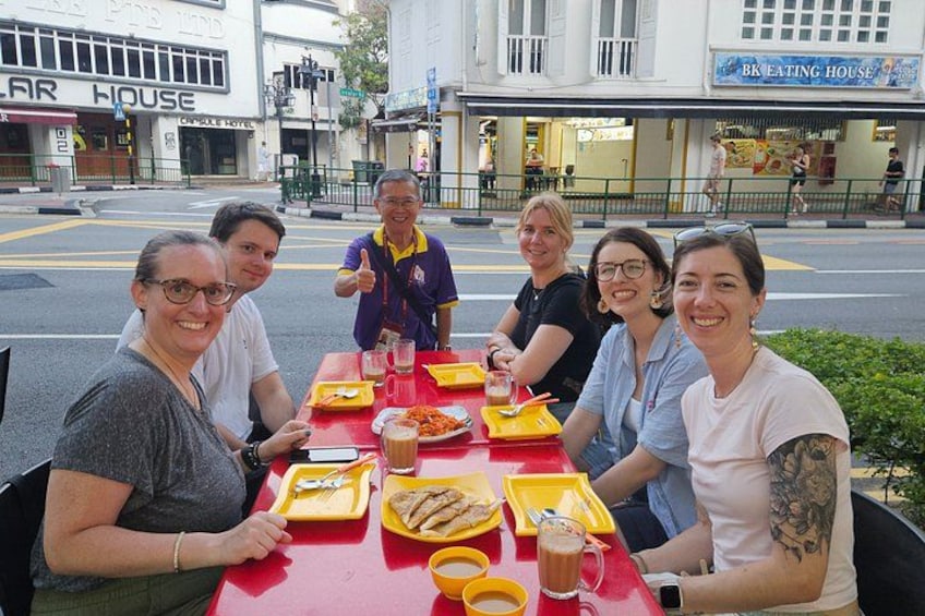 A group of people dining at an outdoor table with food and drinks. 4