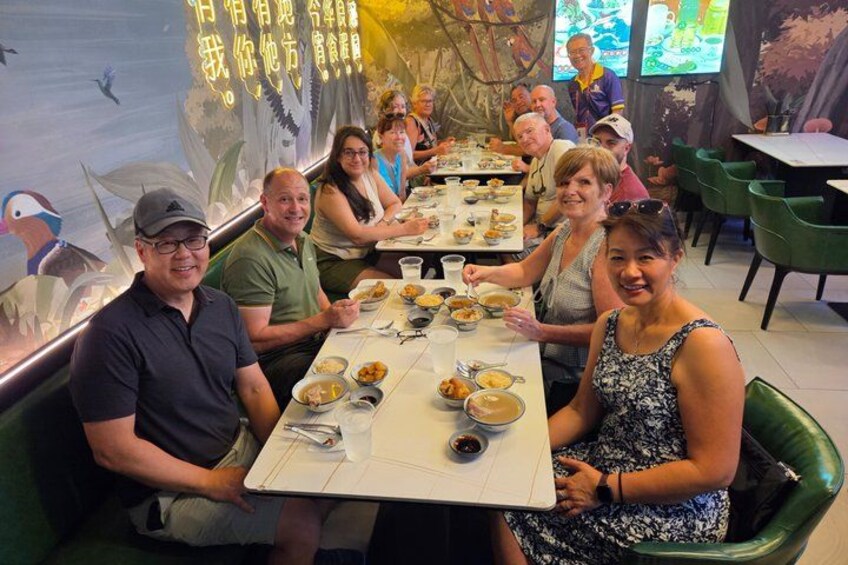 A group of people dining at a restaurant with a mural in the background. 1
