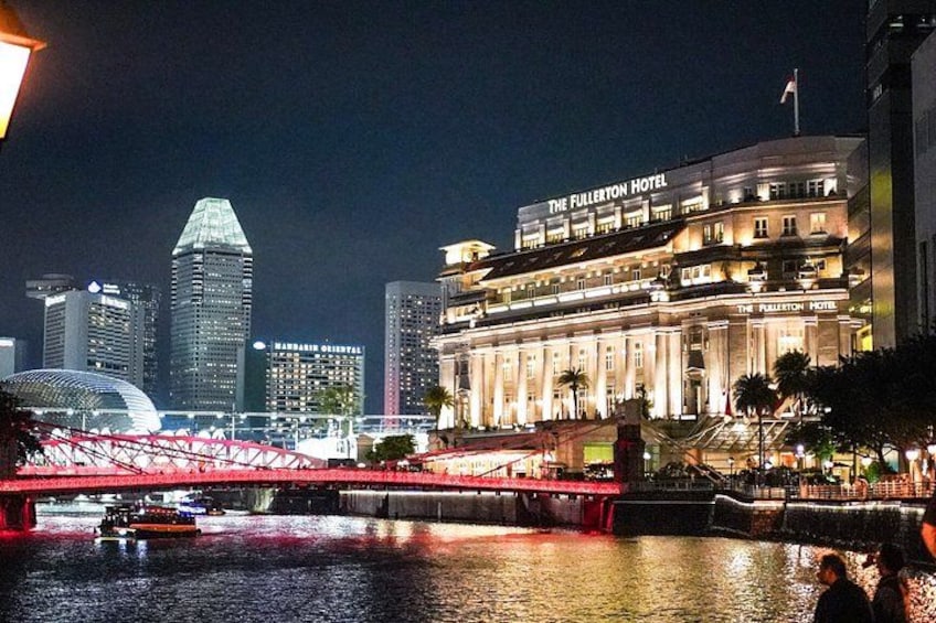 A nighttime cityscape with The Fullerton Hotel, a red bridge, and modern skyscrapers. 2