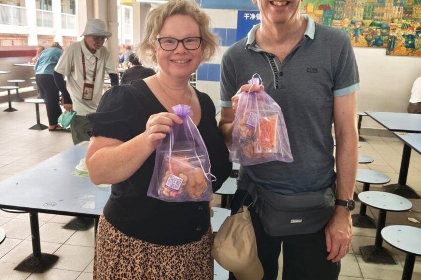 Two people holding plastic bags with food items in a cafeteria setting. 5