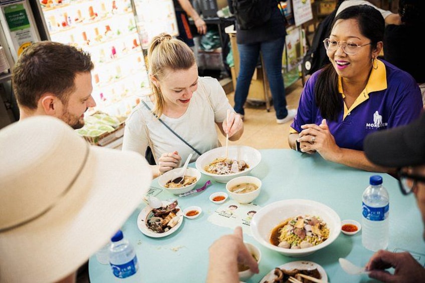 A group of people dining at a table with bowls of food, a water bottle, and a menu. 1