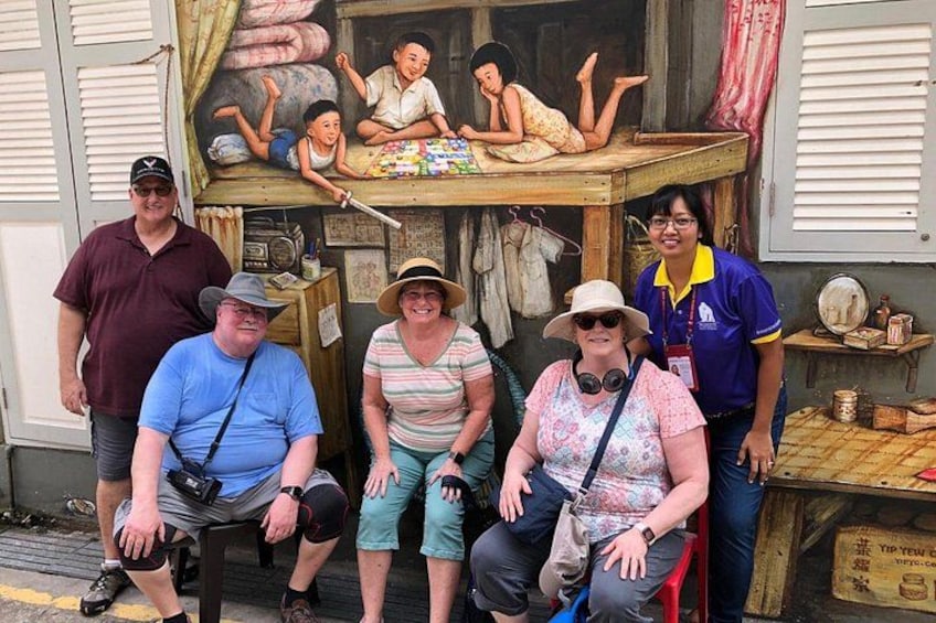A group of people posing in front of a shop with a mural. 1