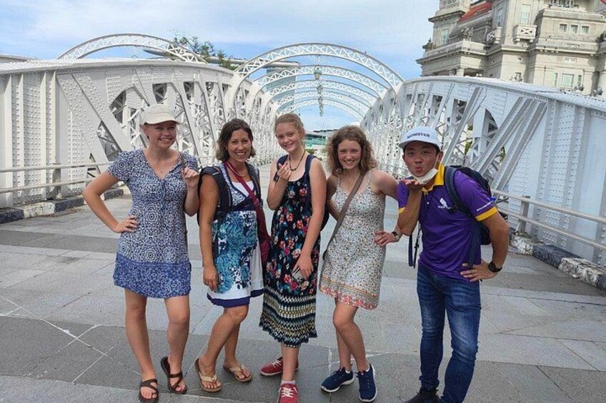 A group of people standing on a bridge with intricate metalwork and a building in the background. 2