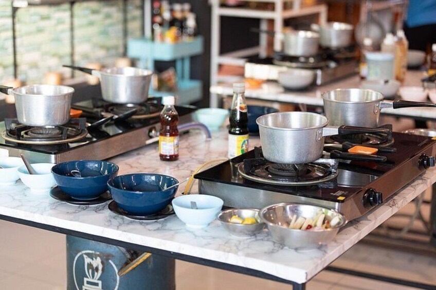 Una cocina con varios fogones, ollas, cuencos y botellas sobre una encimera de mármol. 1