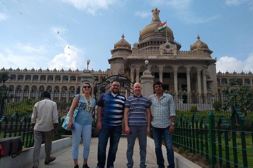 A group of people standing in front of a large, ornate building with domes and a flag. 2