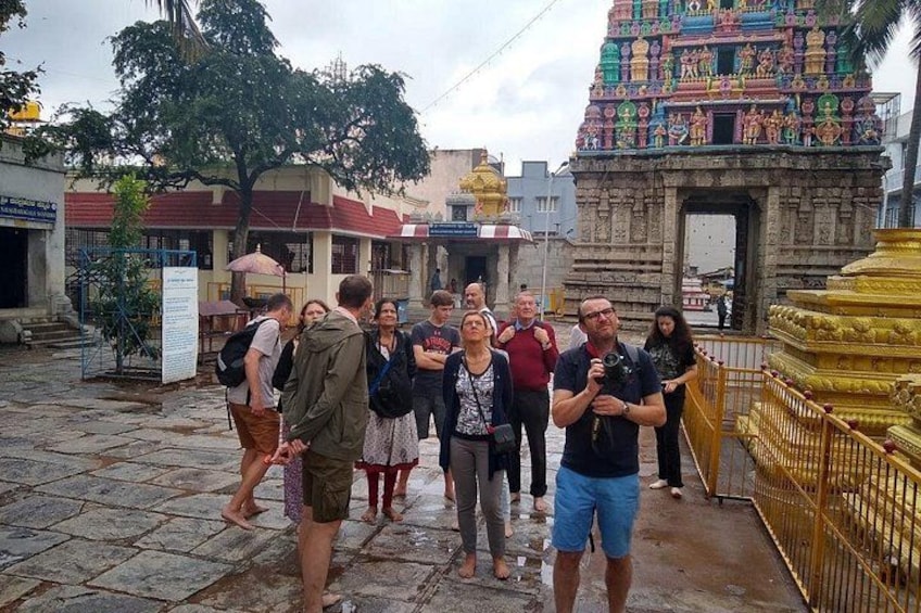 A group of people standing in front of a temple with intricate architecture and a golden structure to the right. 4