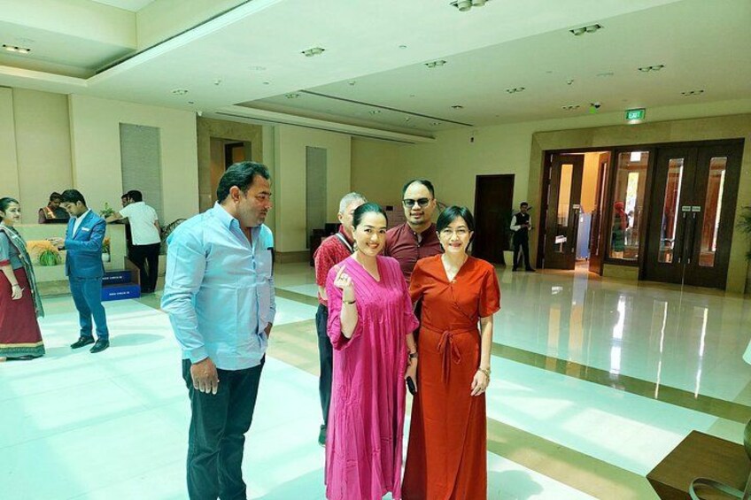 A group of people in a spacious indoor setting with a polished floor and a reception area in the background. 5