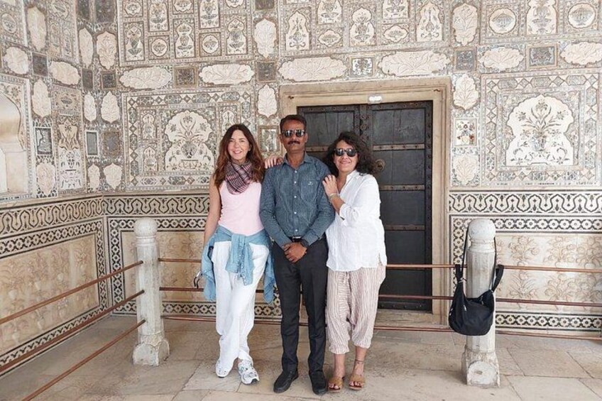 A group of people standing in front of a building with intricate tile work. 2