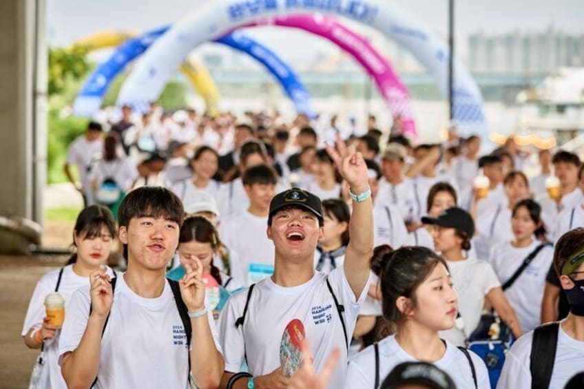 A crowd of people at an outdoor event with a large inflatable arch in the background. 5