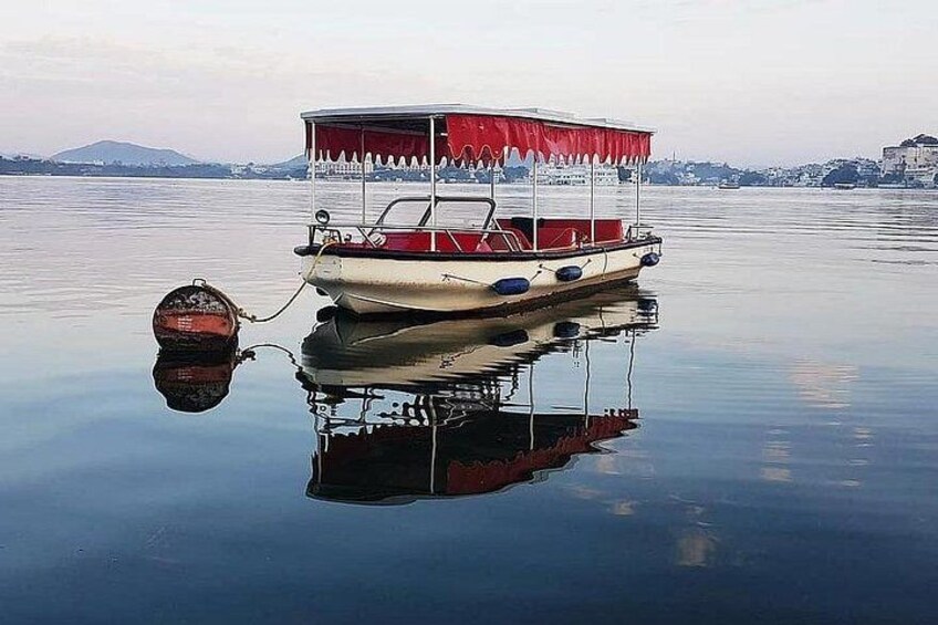 En båd med rødt tag anker i stille vand, der spejler båden og omgivelserne. 3