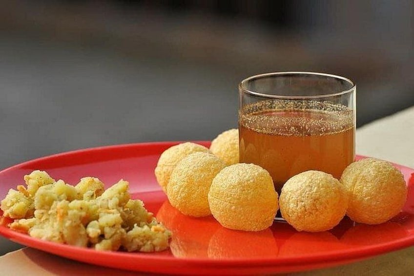 A red plate with round, golden-brown food items and a glass of amber-colored liquid. 4