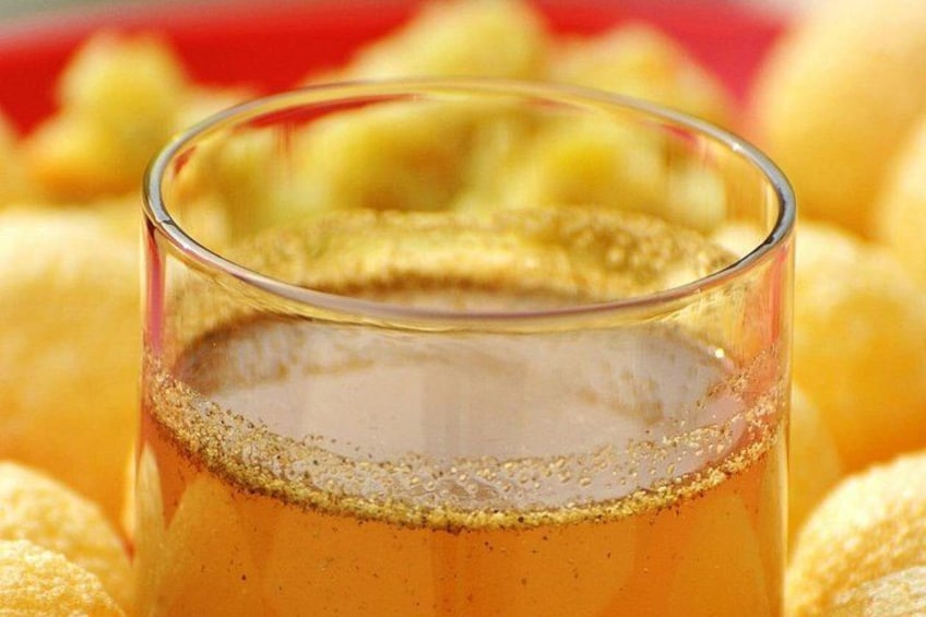 A glass of golden liquid with a frothy top, surrounded by round, yellow objects. 5