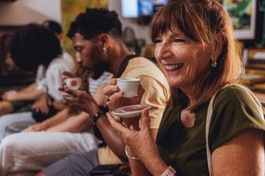 A person holding a cup, seated in a public space with other individuals. 5