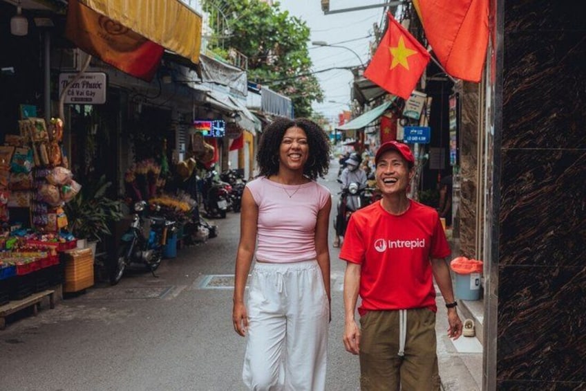 A street with shops, a Vietnamese flag, and a person in a red shirt. 2