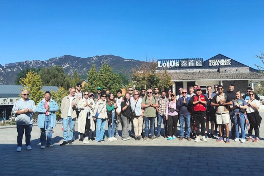 Un gruppo di persone in piedi davanti a un ristorante chiamato Lotus, con montagne sullo sfondo. 2