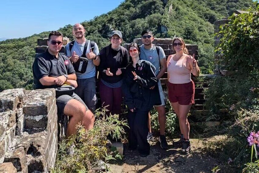 A group of people standing on a stone wall with greenery in the background. 3
