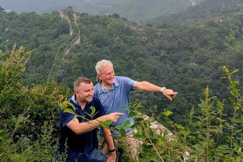Two people standing on a cliff overlooking a lush valley with a winding path. 2