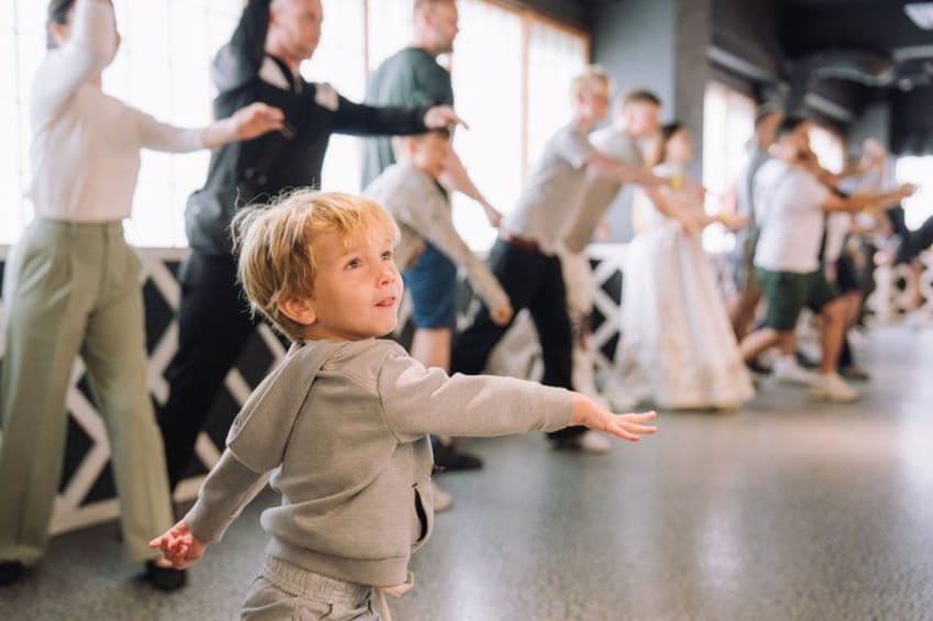 Una clase de baile con participantes con diferentes vestimentas, incluyendo a un niño con un suéter gris. 5
