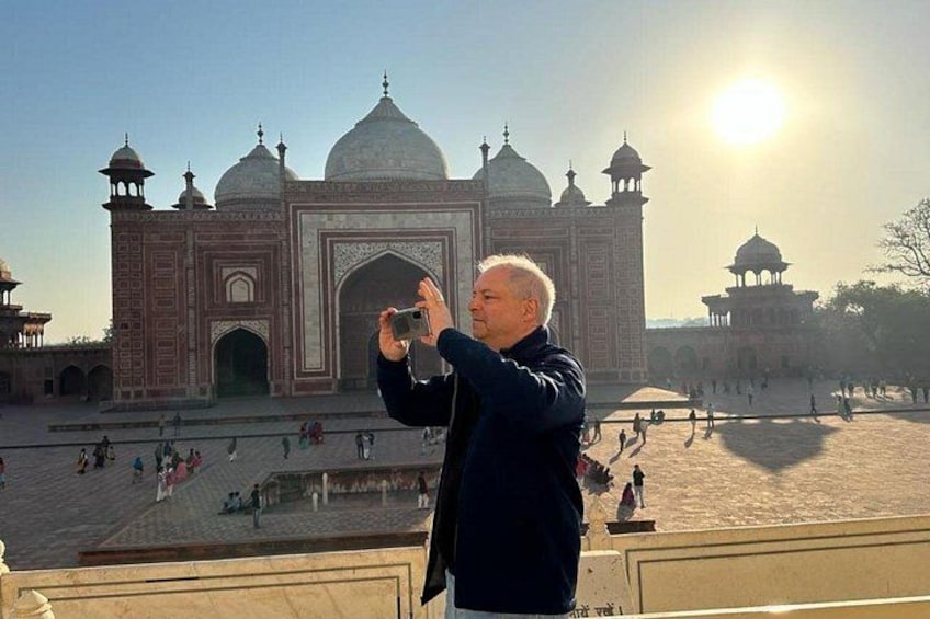 Eine Person fotografiert den Taj Mahal, wobei die Sonne im Hintergrund zu sehen ist. 2