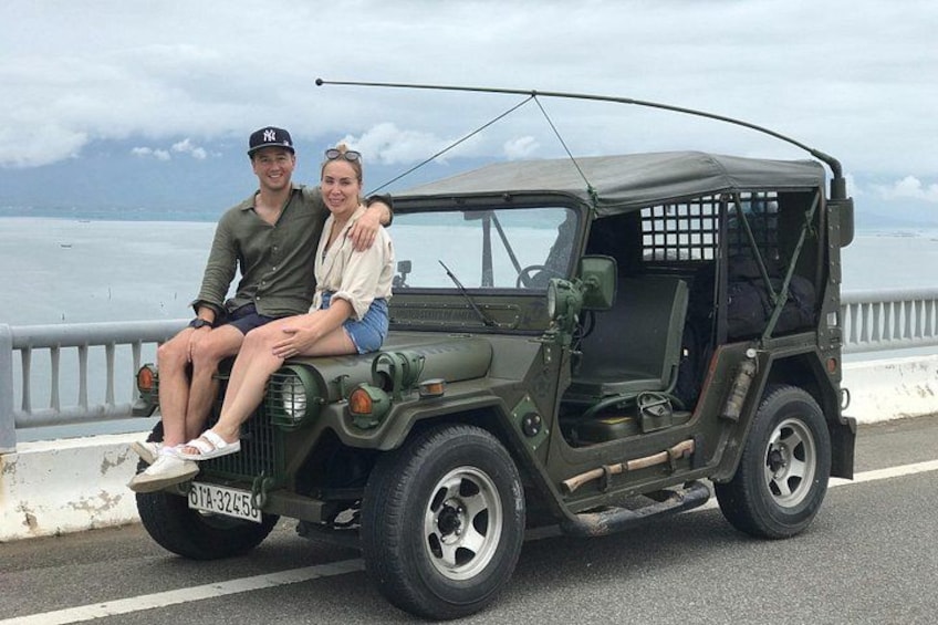 A green jeep with a license plate, a person in a cap, and another in a white shirt. 4