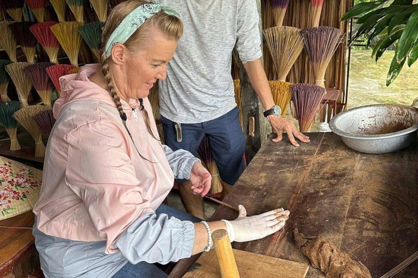 A person kneeling on a wooden floor, working with a rolling pin and dough. 3