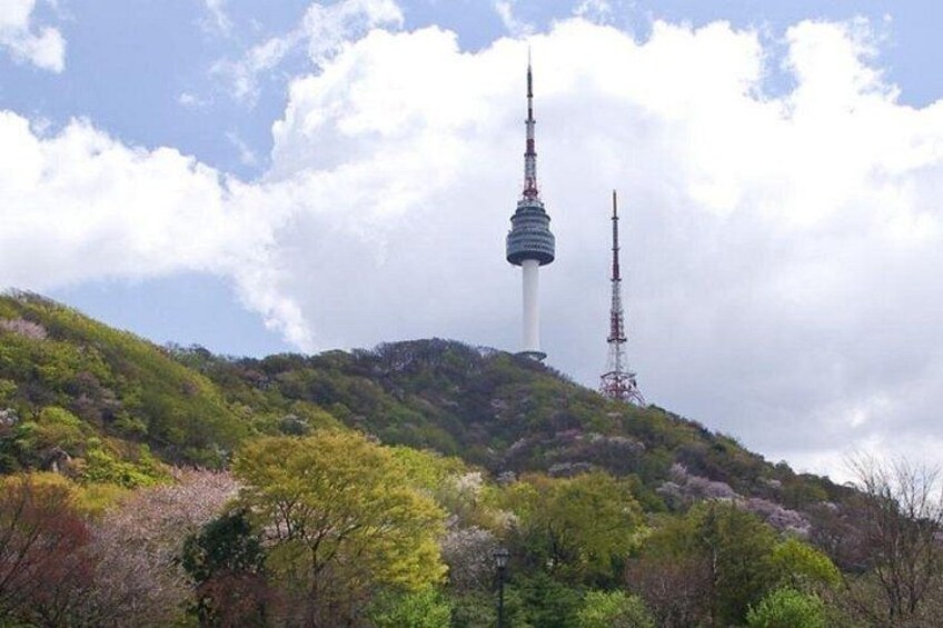 Ein Turm auf einem Hügel, umgeben von Bäumen, mit blauem Himmel. 2