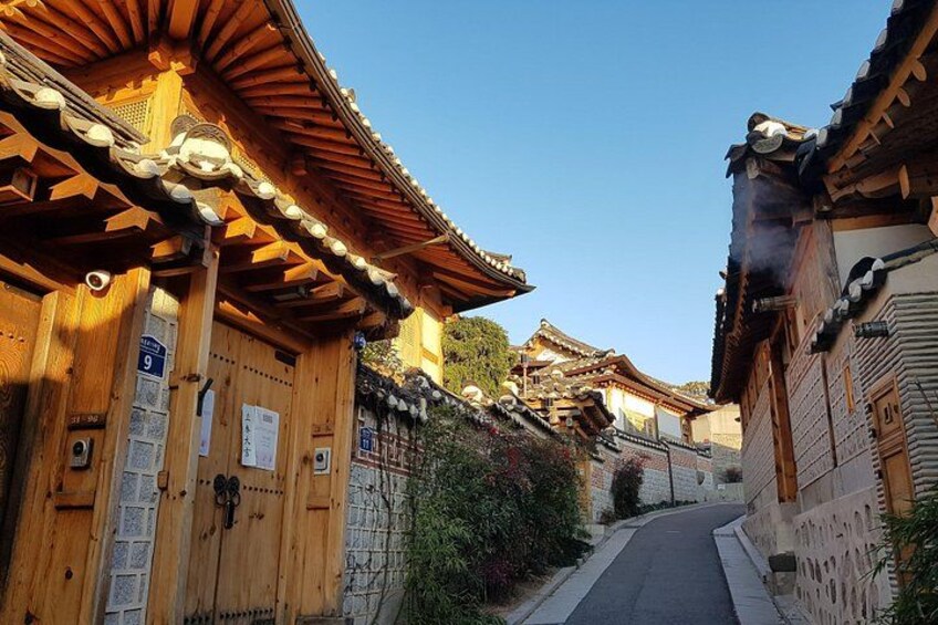 Ein traditionelles Holzhaus mit Ziegeldach, eine enge Gasse und eine Steinmauer. 3